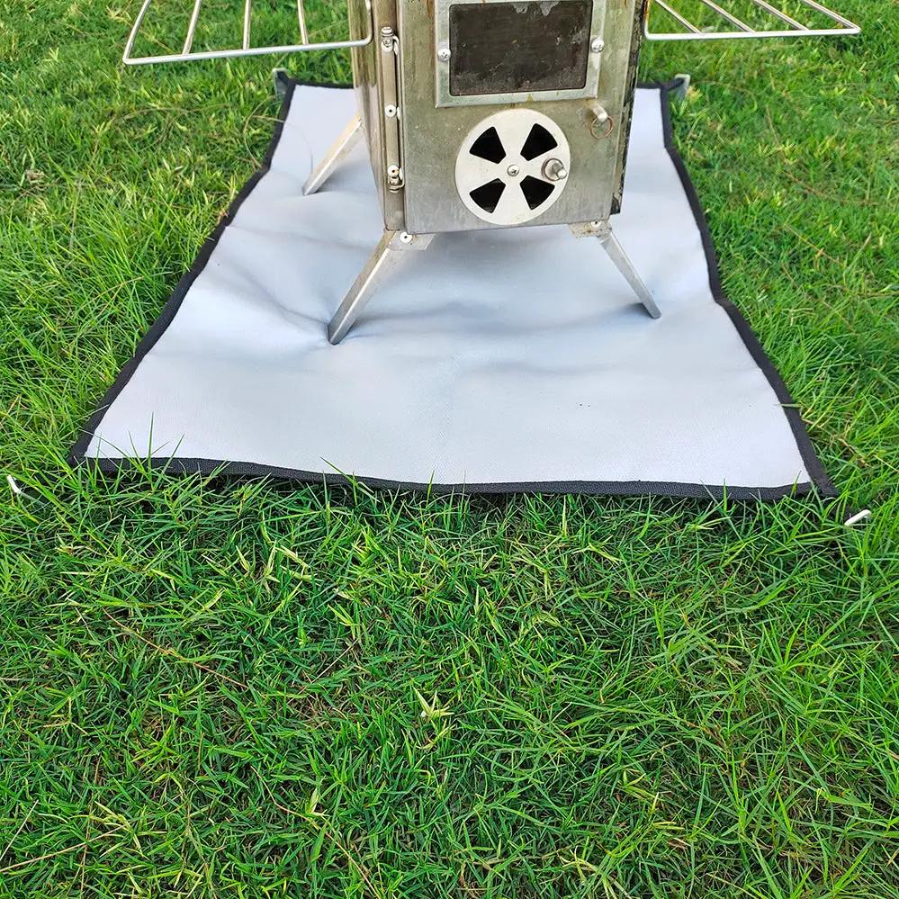 Camping fireproof cloth BBQ grill mat; light-gray with black edge, by Simples Market under a stove on grass.