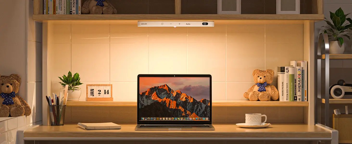 WILLED warm-light motion-sensor LED light bar under shelf, lighting a desk with laptop, plant, and teddy bears.