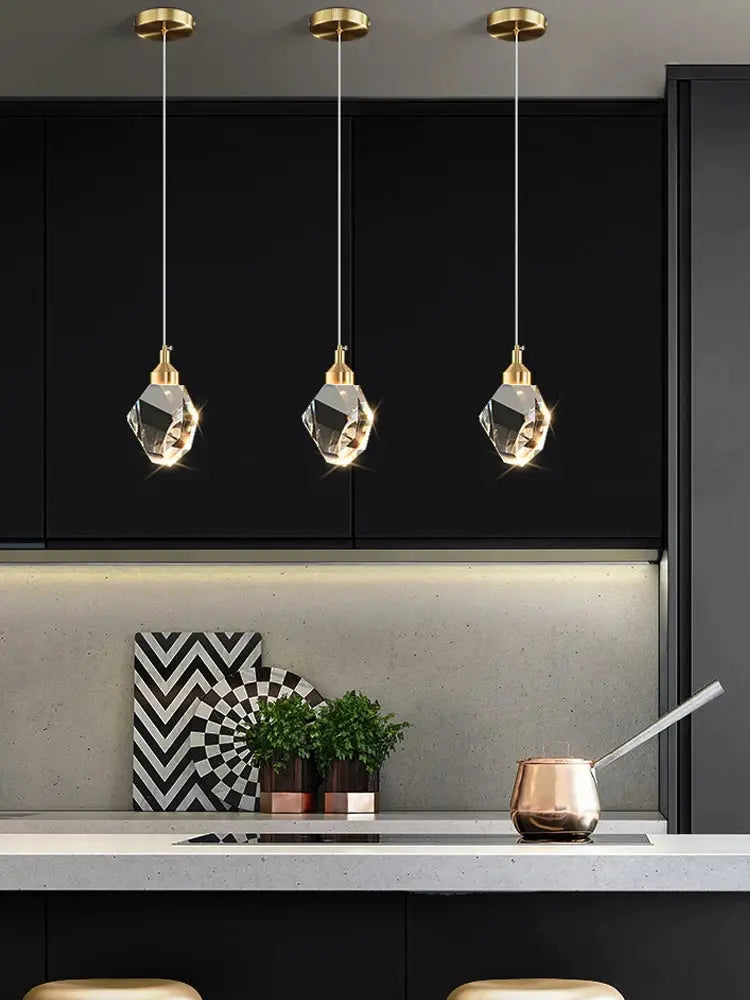Three ceiling pendant lamps by Simples Market with gold brass tops and crystal geometric shades.