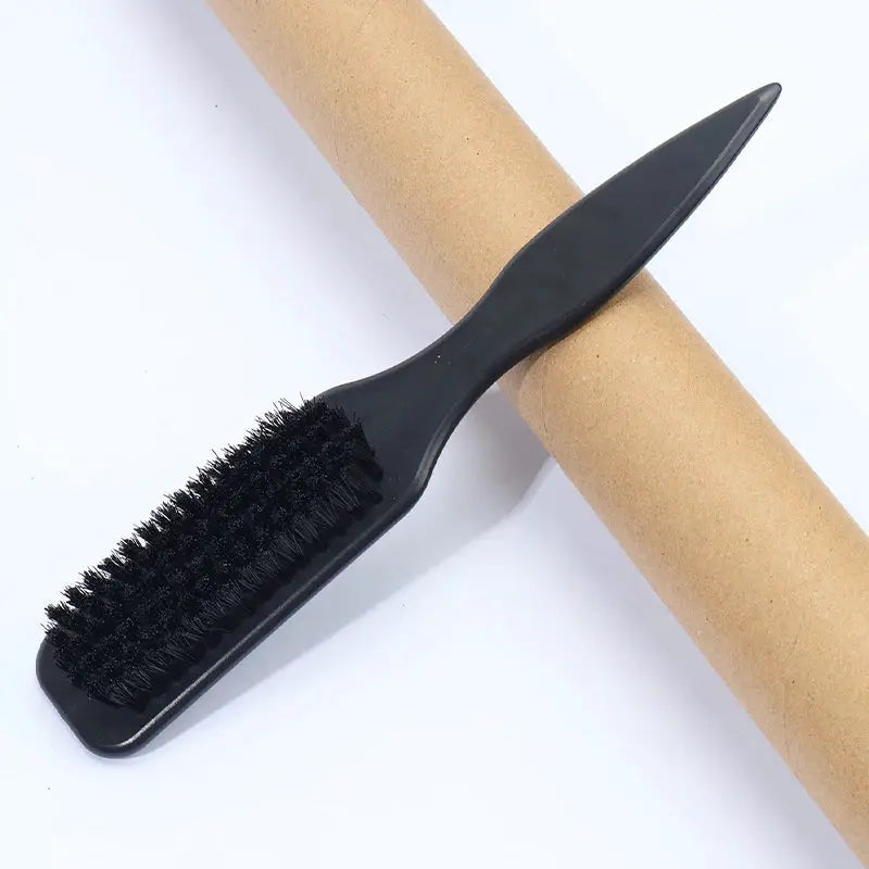 Black plastic slick-back hair brush resting on a cardboard roll for sleek ponytails