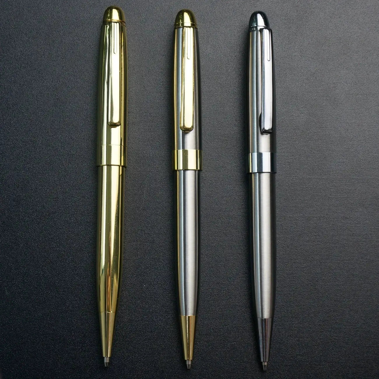 Ballpoint pens set by Simples Market; three retractable metal pens in gold, silver, and gunmetal.