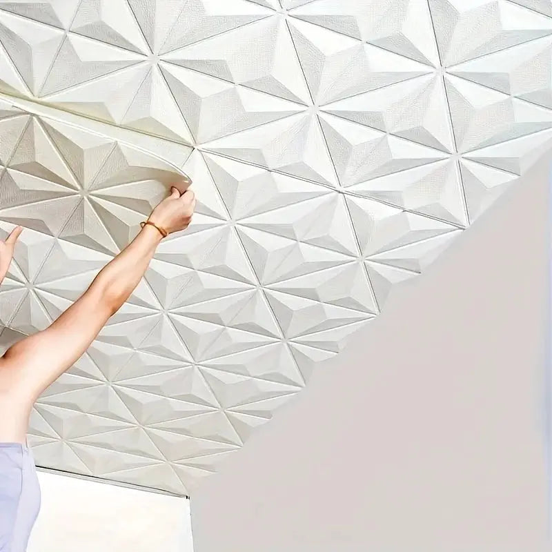 3D self-adhesive foam tile for walls and ceilings, white geometric pyramid pattern (35×35 cm); being applied.