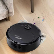 Robot vacuum cleaner, black, on a wooden floor with scattered debris.