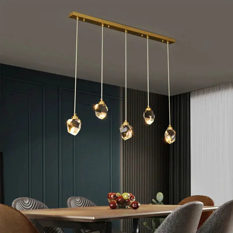 Ceiling pendant lamp set of 5 crystal pendants with a gold bar for modern dining room lighting.