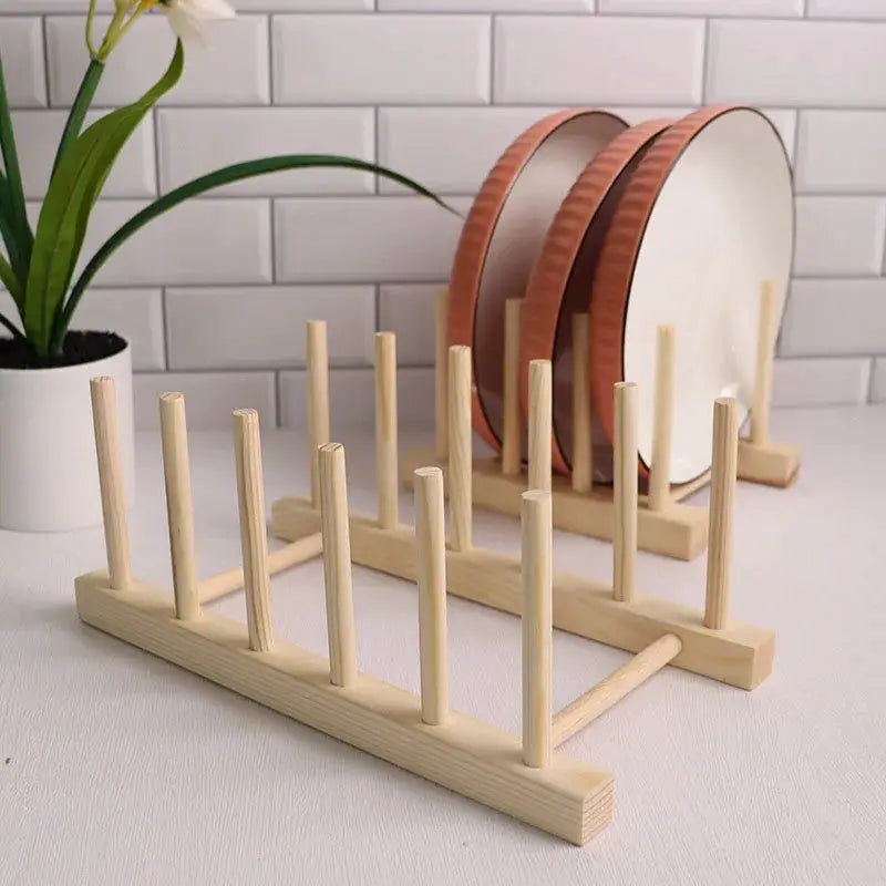 Two natural wooden dish-drying racks with vertical pegs for plates in a kitchen storage organizer
