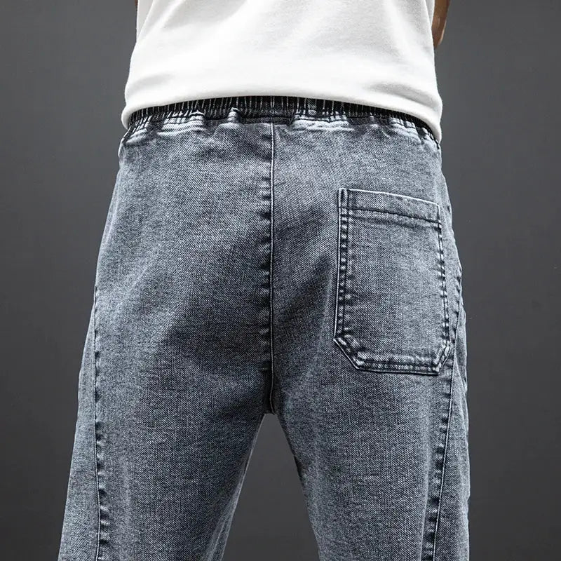Men's gray denim cargo jogger jeans with back pocket and elastic waistband.