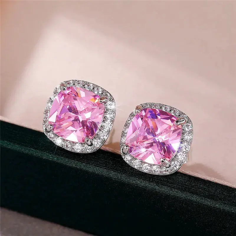 Pair of pink cubic zirconia cushion-cut stud earrings with a halo of clear stones in a silver-tone setting