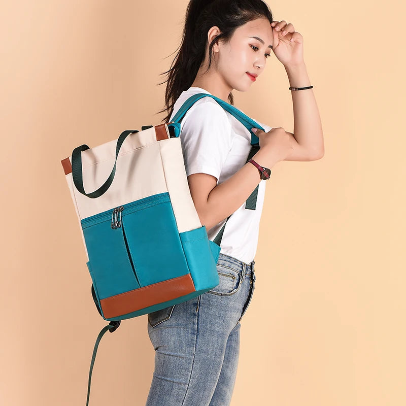 Womens waterproof Oxford backpack in teal with beige top panel and brown accents, front zip pocket