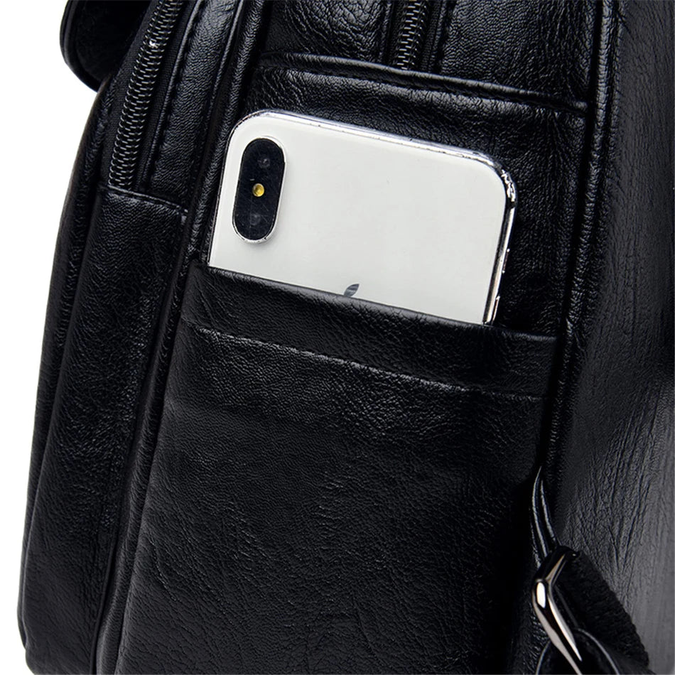 Genuine women's soft black leather backpack with front pocket holding a smartphone