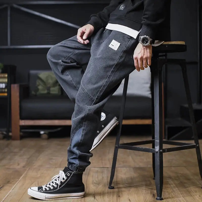 Plus-size men's denim cargo jogger pants with cargo pockets, loose ankle-length in dark blue.
