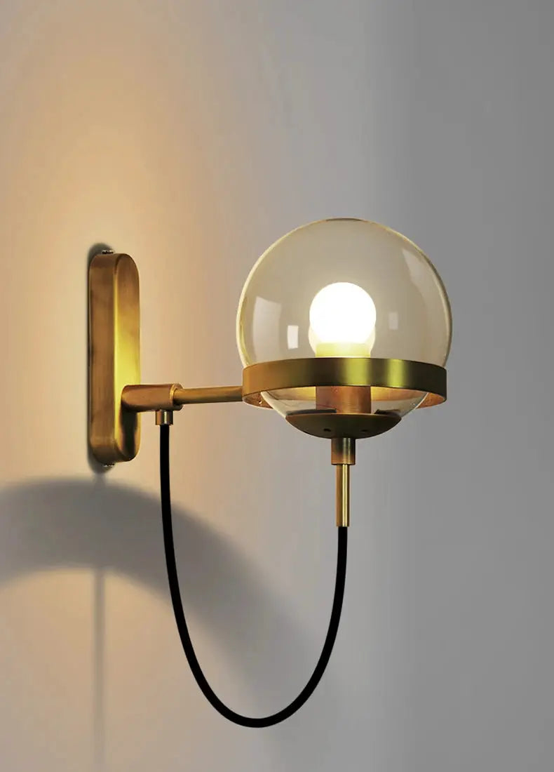 Modern glass ball wall lamp with brass arm and black cord, E27 bulb.