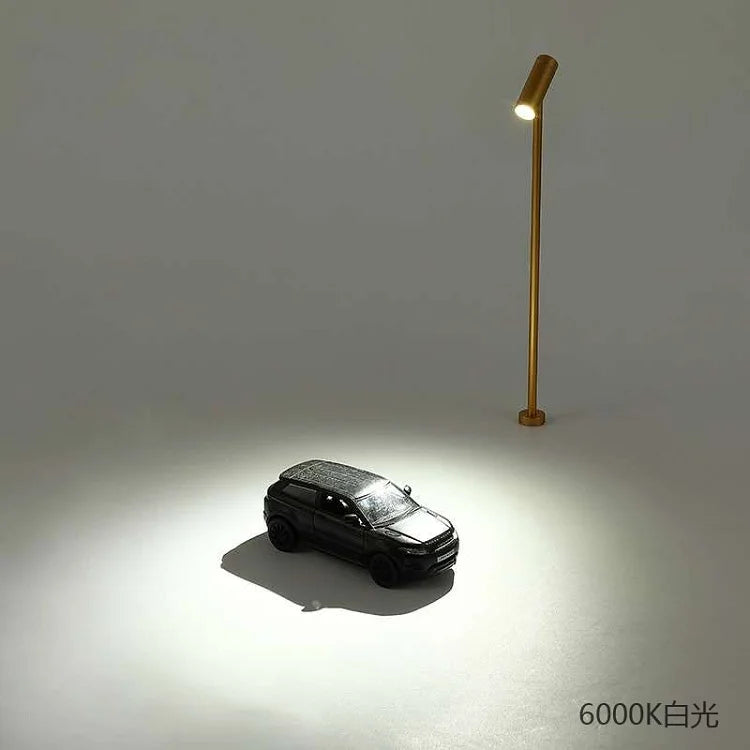 Gold LED spotlight upright lamp lighting a small toy car on a white display surface