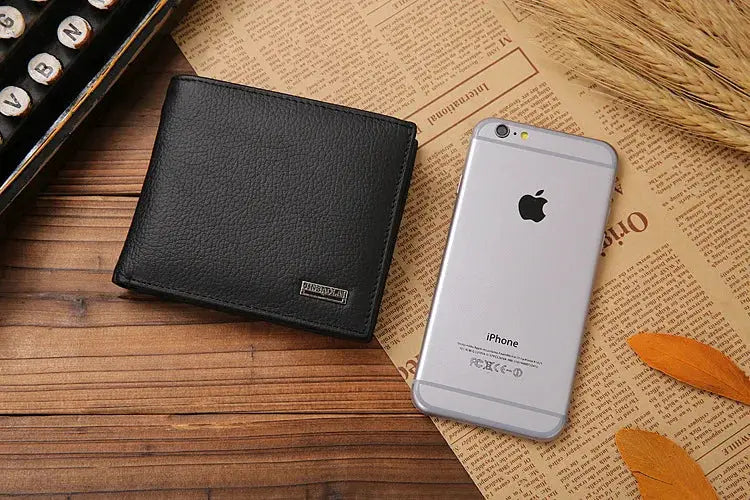 Classic short leather men's wallet with coin pocket, black by Simples Market, beside an iPhone on a wooden desk.