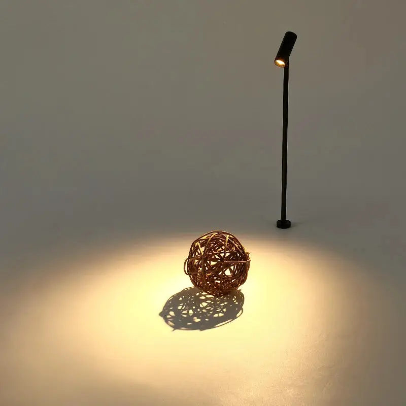 LED spotlight post lamp, black upright with rotatable head, lighting a wicker ball display