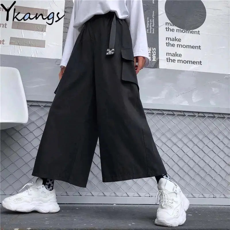 Cargo pants, black wide-leg with large side pockets; white top and chunky white sneakers