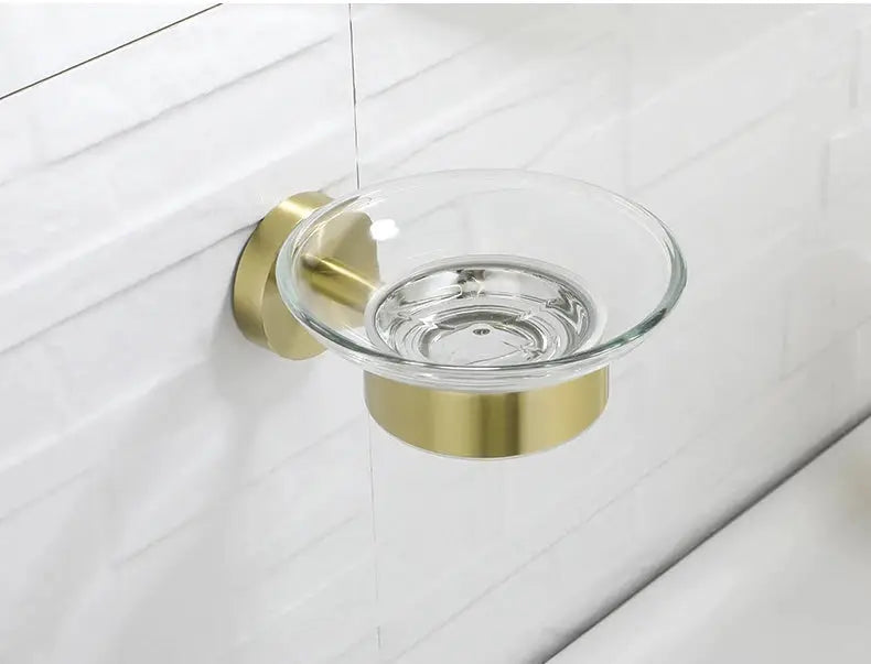 Bathroom soap dish holder with a clear glass dish and brushed gold wall-mount bracket for modern bathrooms