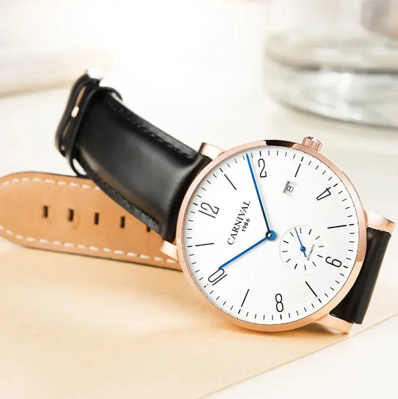 Carnival men's luxury watch with rose-gold case, white dial, blue hands, date window, and black leather strap