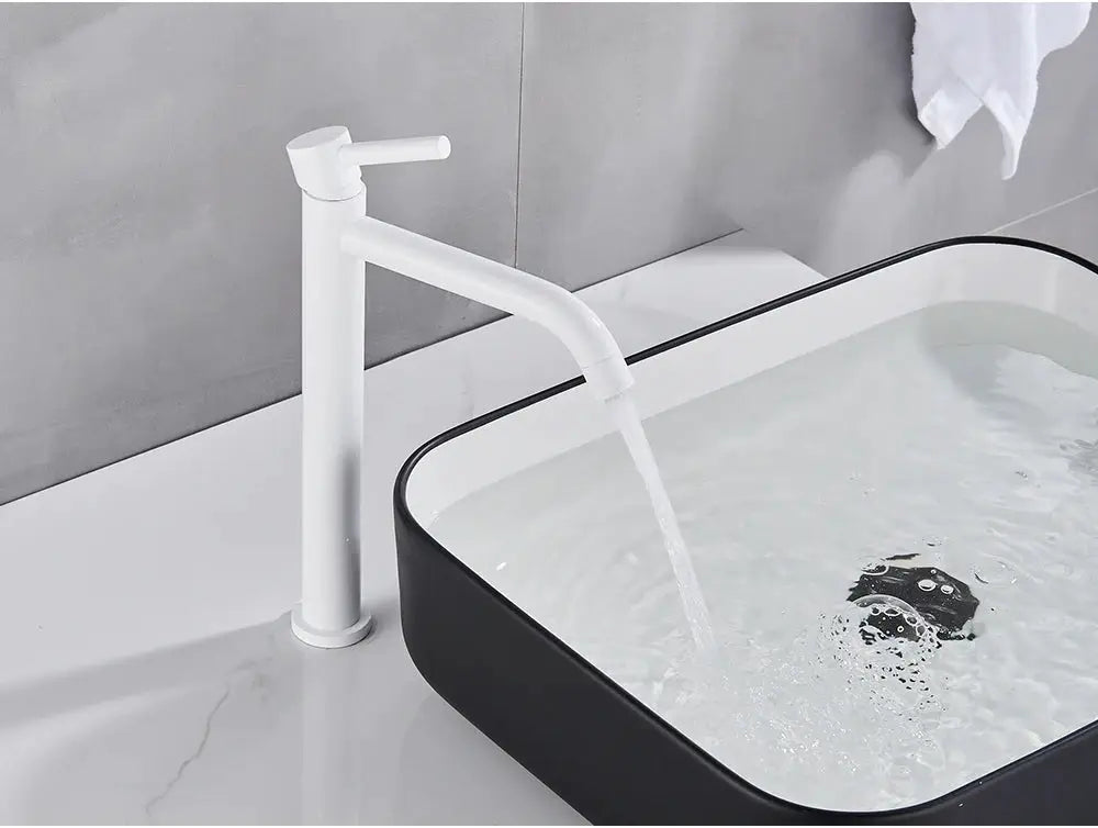 White bathroom basin faucet with tall cylindrical body and curved spout, water flowing into a black-rimmed sink.