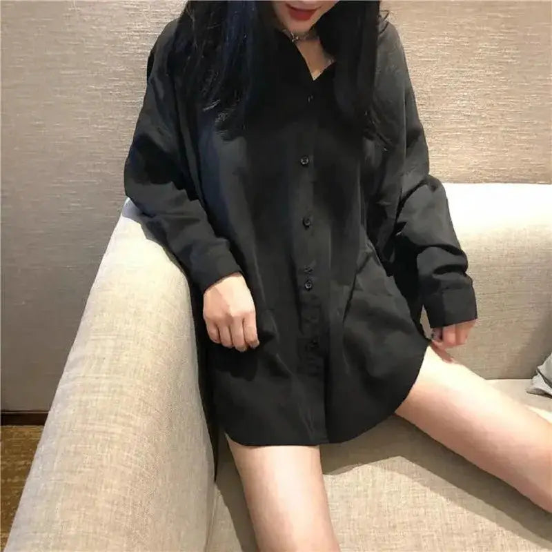Black oversized button-up shirt with long sleeves worn as a casual tunic on a model