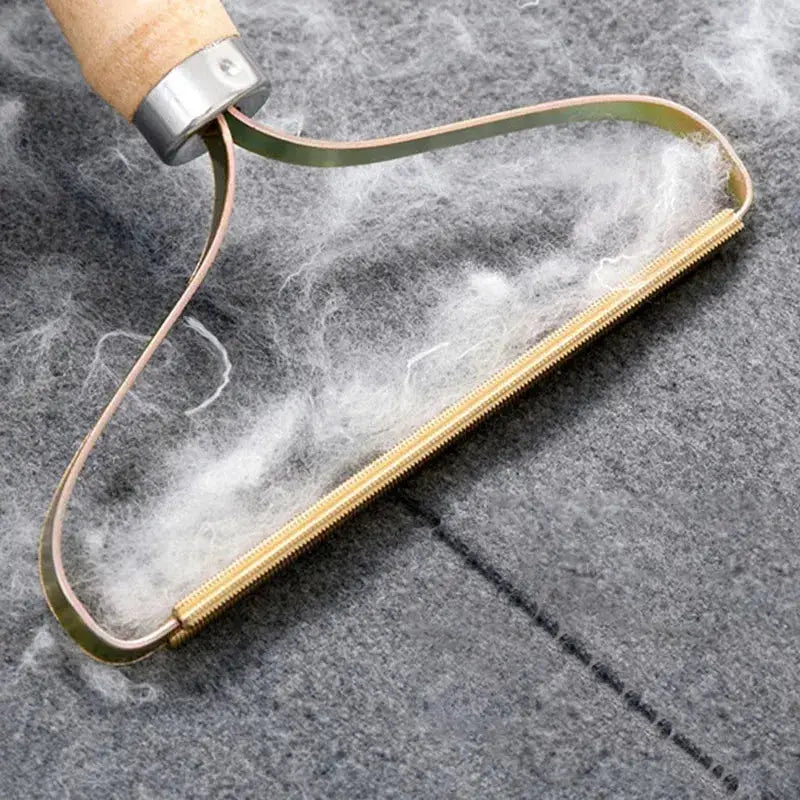 Portable lint remover brush with clear plastic head and gold-tone frame removing pet hair from fabric
