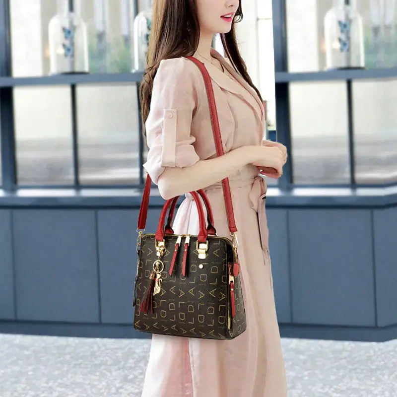 Fashion English Letter handbag in black PU leather with red top handles and tassel.