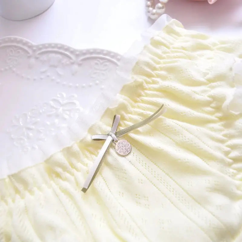 Panties in pale yellow cotton with ruffle trim, bow and decorative charm.