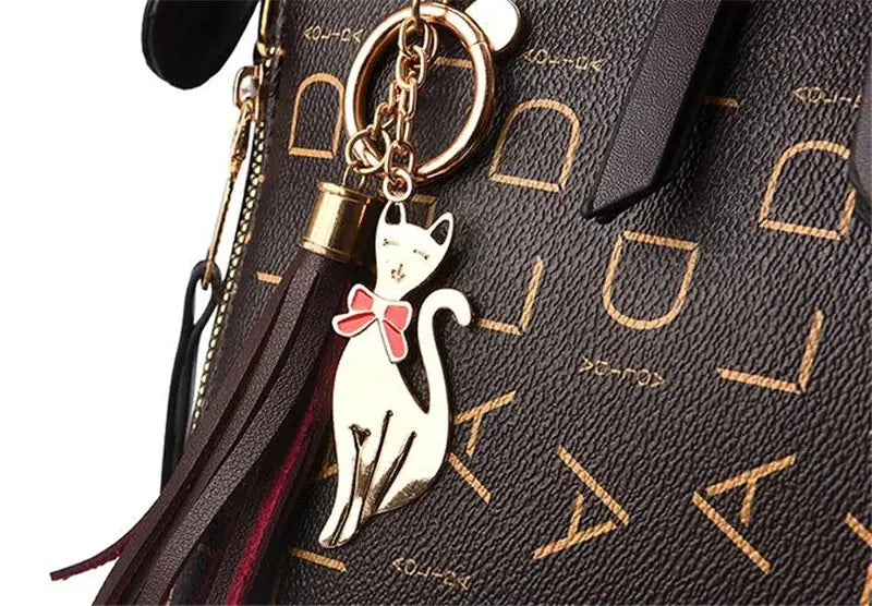 Fashion English Letter Handbag in dark PU leather with tassel top-handle and cat charm keychain.