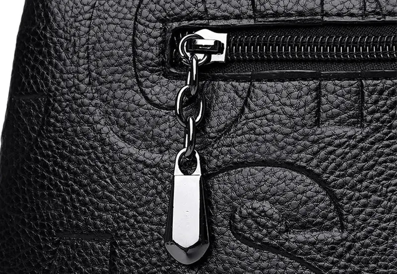 PU leather crossbody bag in black with silver zipper pull and decorative metal tassel.