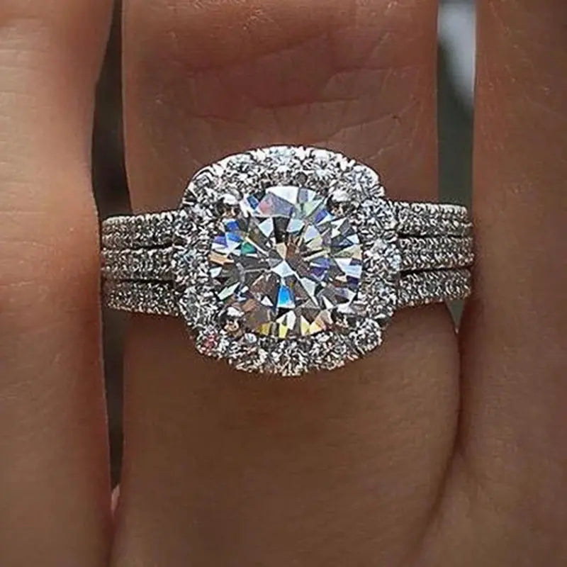 Huitan trendy women ring with a large cubic zirconia center stone in halo setting on a triple-row brass band