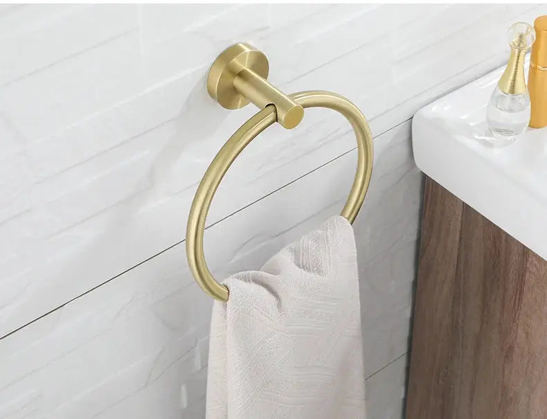 Brushed gold towel ring wall mount with white towel in bathroom.