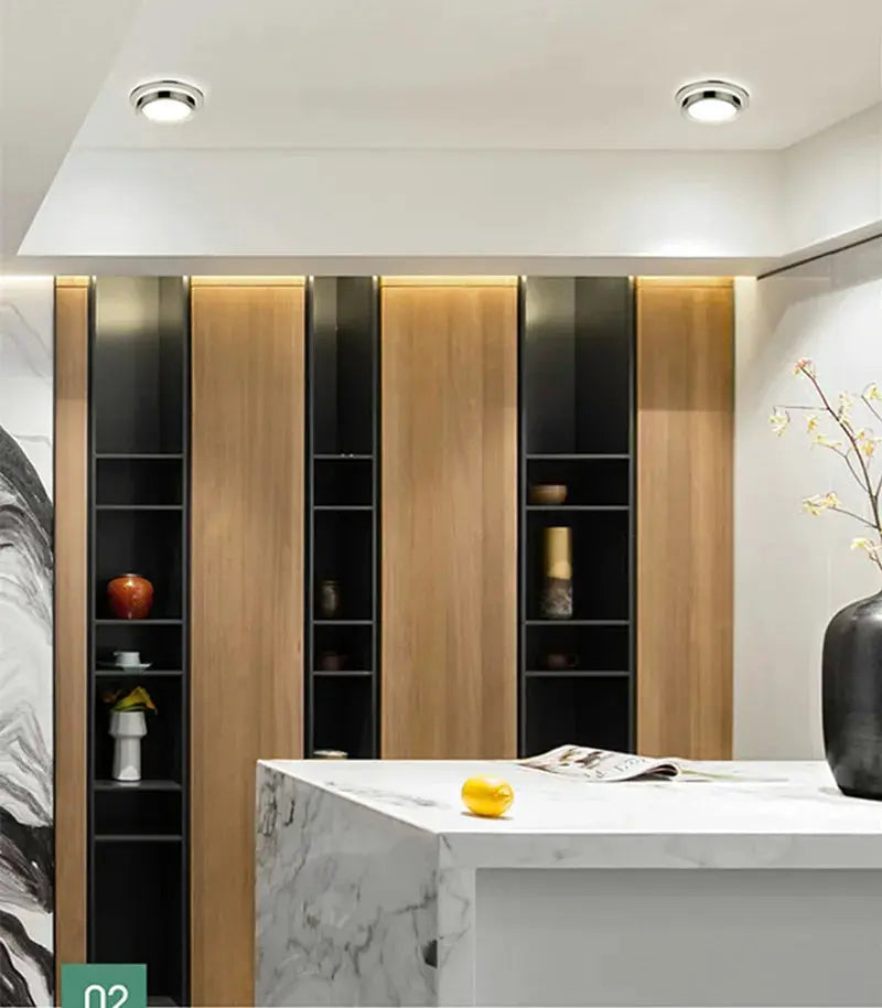 Chrome round recessed LED downlights (2) installed in white ceiling over a modern kitchen island
