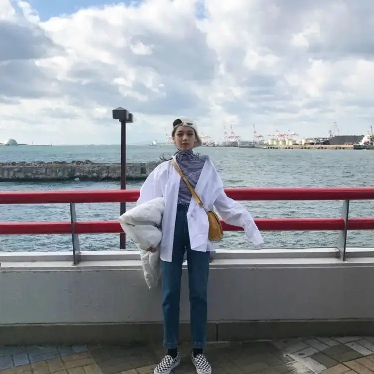 Zadily white oversized button-up shirt on a model; casual long-sleeve tunic by the waterfront