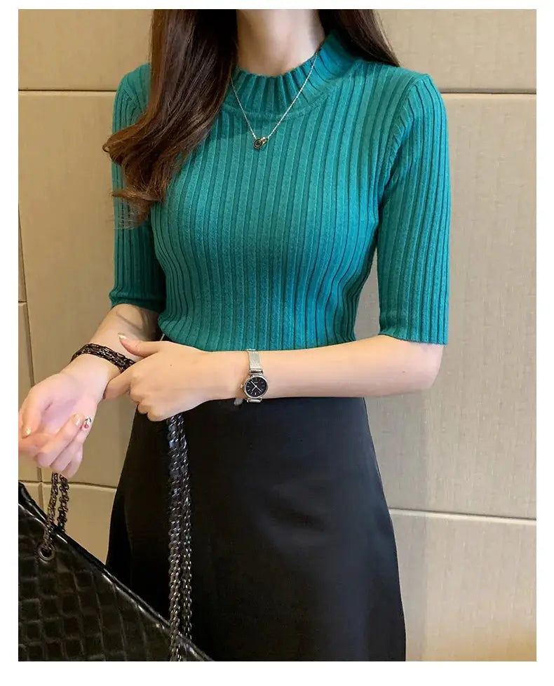 Teal ribbed knit blouse with short sleeves and crew neck; shown with black skirt and chain bag