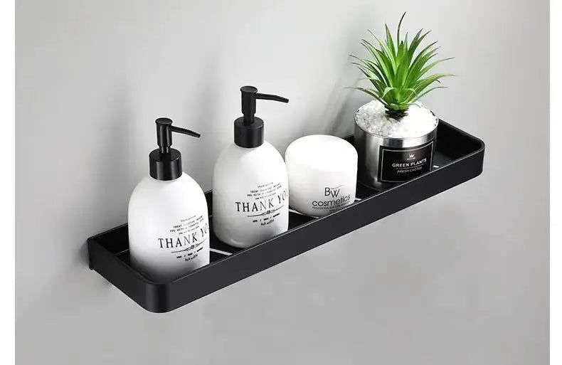 Bathroom corner shelf in black aluminum, wall-mounted, displaying pump bottles, a lotion jar, and a small plant