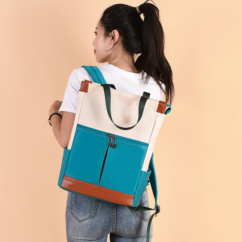 Women's two-tone teal and beige Oxford backpack with brown base and front zip pocket
