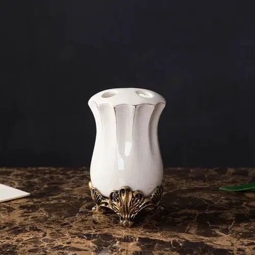 White ceramic toothbrush holder on an ornate gold-tone leaf pedestal, European style bathroom set accessory.