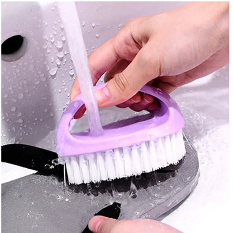 Purple egg-shaped cleaning brush with white bristles under running water; versatile household scrub tool.