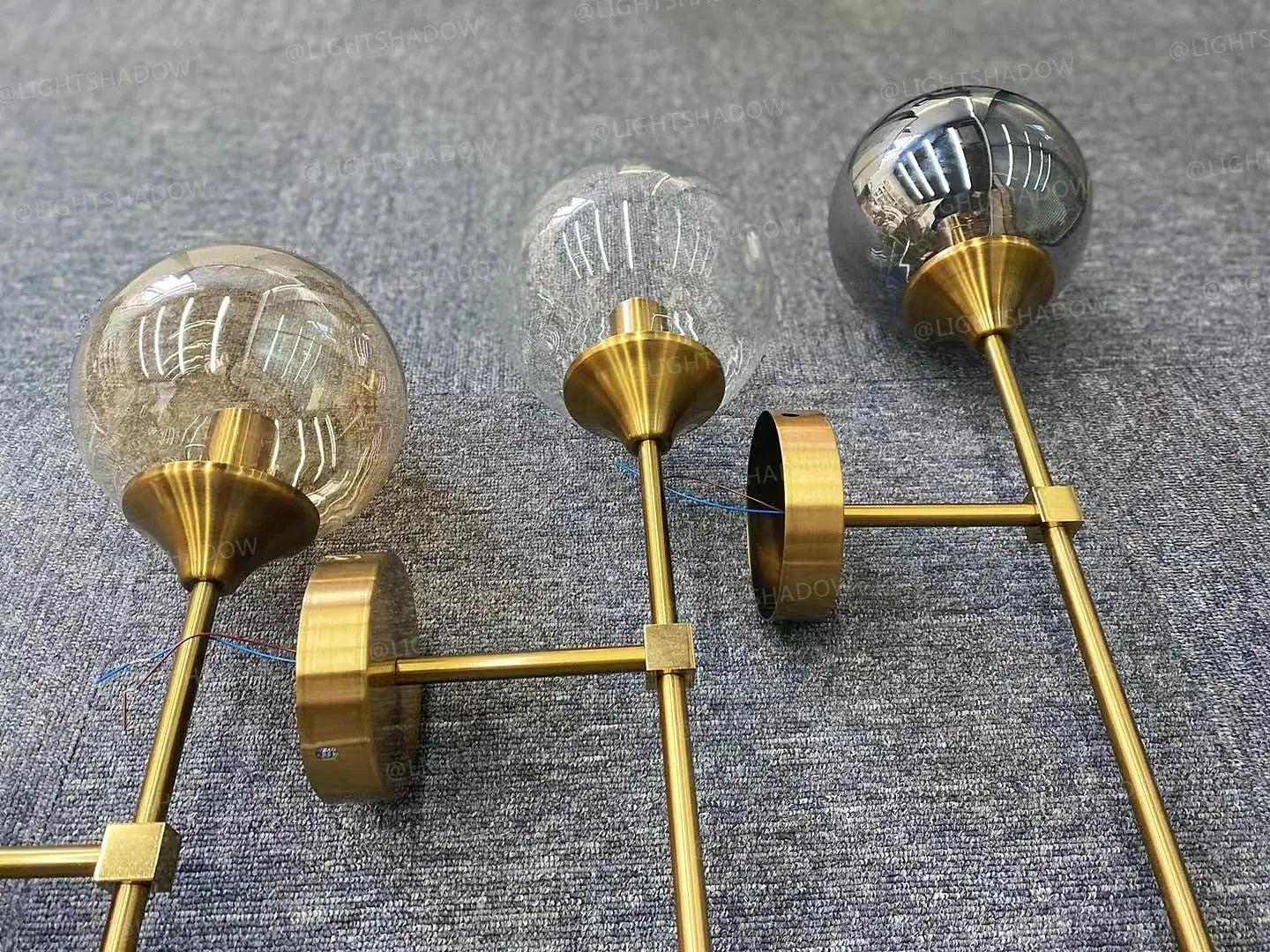 Modern glass wall lamp by Simples Market with brass finish and three clear globe bulbs