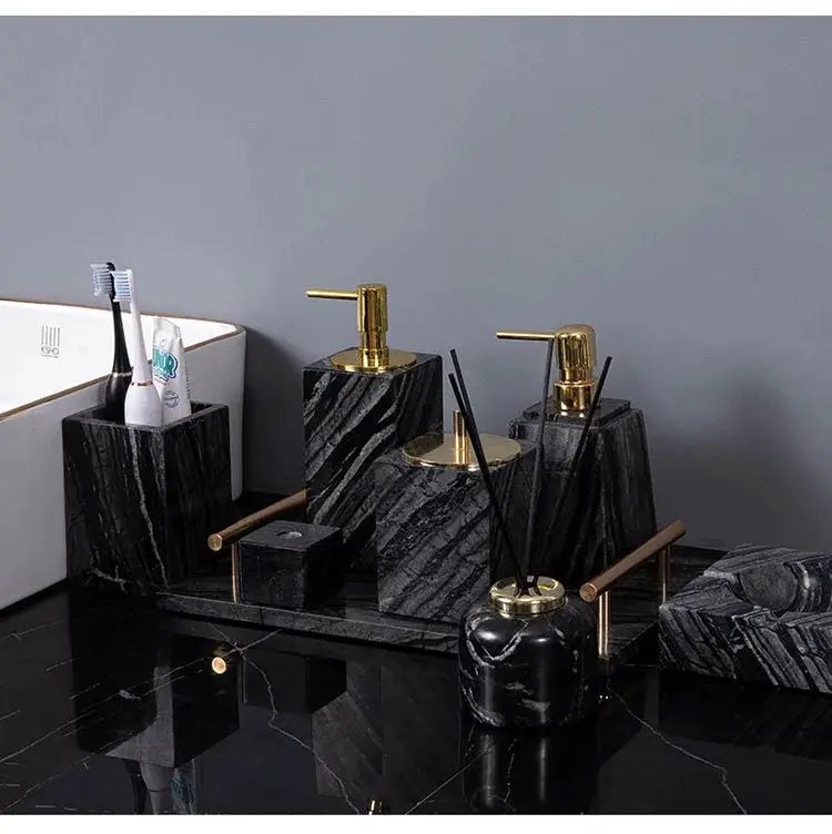 Black-veined marble bathroom accessories set with gold fixtures; includes soap dispenser, toothbrush holder, and tray.
