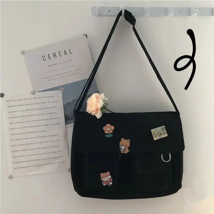 Women's black canvas messenger bag with playful patches and front pockets
