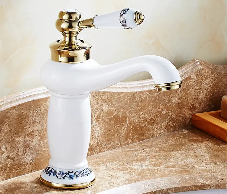 Bathroom faucet with white ceramic body, single-handle lever, and gold brass fittings on a marble countertop