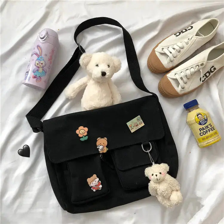 Black canvas messenger bag with cute flower and bear patches and plush teddy keychain