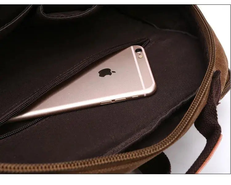 Vintage canvas backpack in brown with a zip pocket and a smartphone inside.