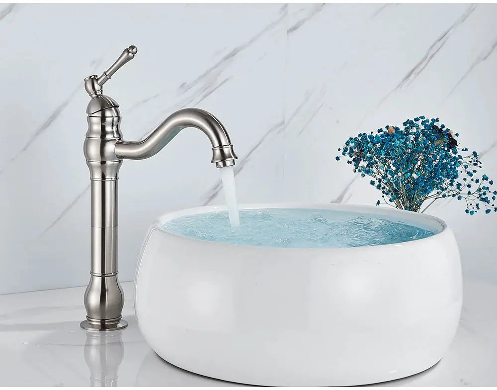 Antique-brass vessel basin faucet, deck-mounted, single-hole with curved spout over a white ceramic bathroom sink