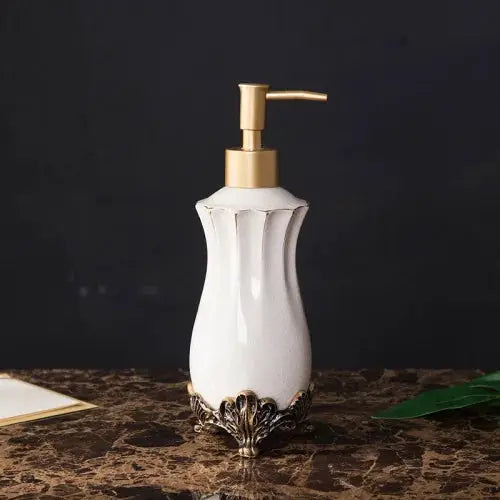 Soap dispenser, European-style white ceramic with a gold pump and ornate metal base.