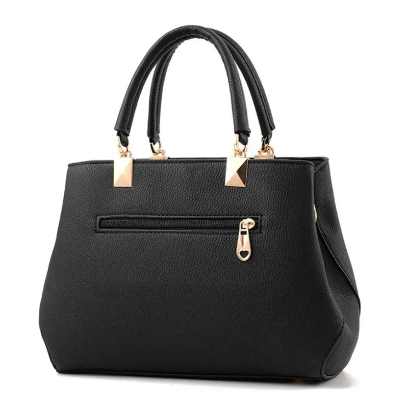 Simples Market black textured leather shoulder bag with dual top handles and gold-tone hardware; zip pocket.
