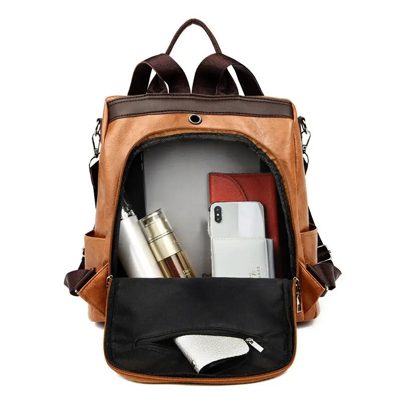 Brown PU leather anti-theft backpack with front pocket open, showing wallet and smartphone inside