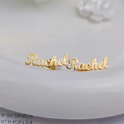 Custom name earrings in gold-tone stainless steel; minimalist script name studs.