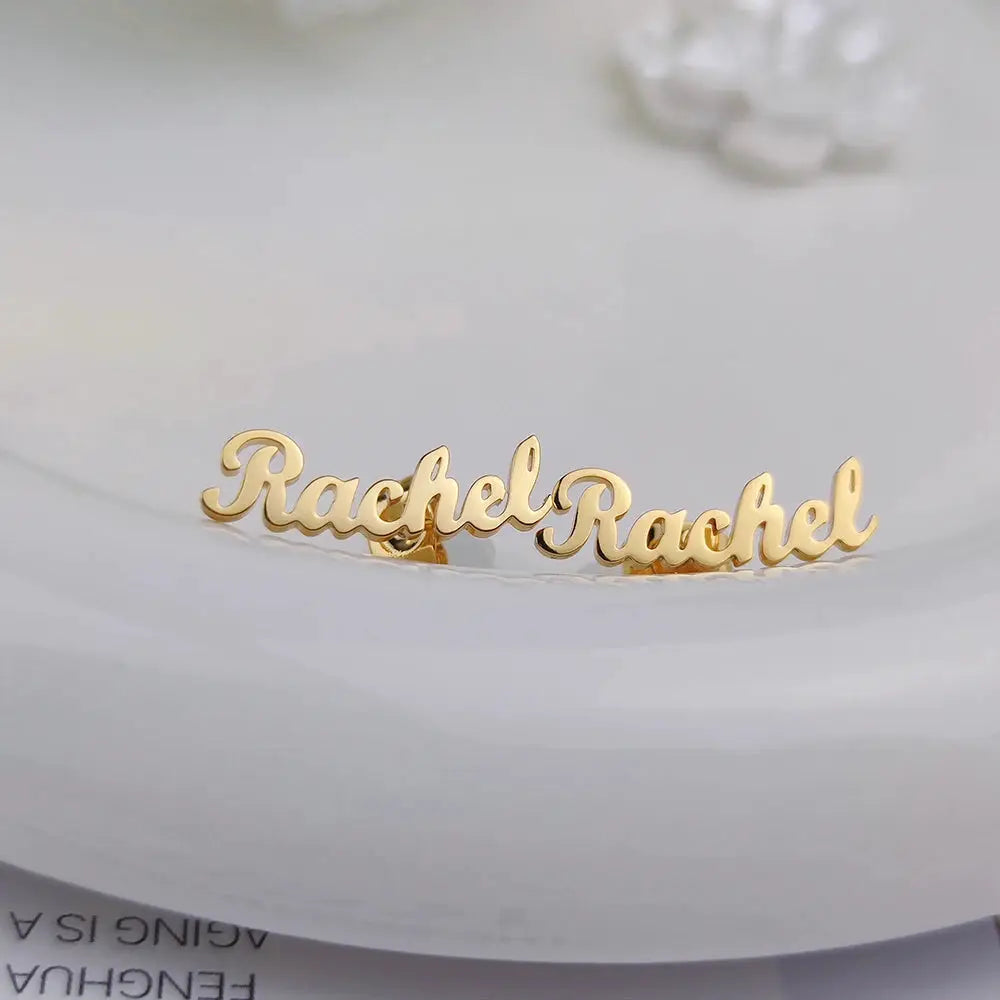 Custom name earrings in gold-tone stainless steel; minimalist script name studs.