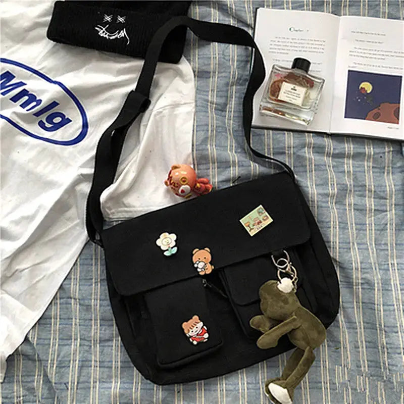 Women's black canvas messenger bag with front pockets and cartoon patches.